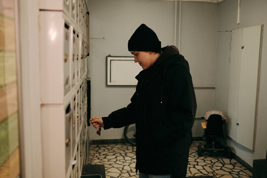 Young woman checking mailbox in apartment building hallway. Concept of communication, delivery, daily routine, and residential lifestyle.