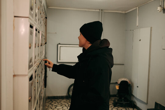 Young woman checking mailbox in apartment building hallway. Concept of communication, delivery, daily routine, and residential lifestyle.