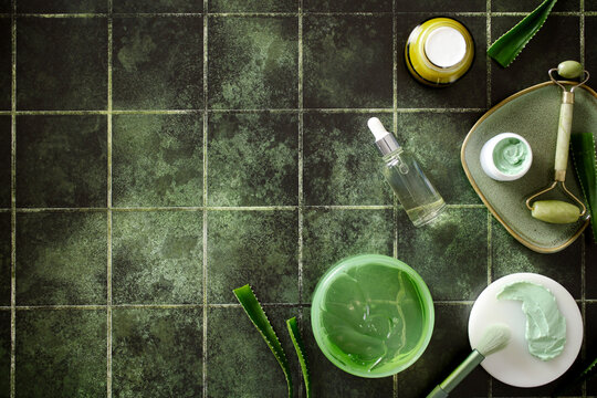 Organic skincare products and aloe vera with large copy space on green tile background