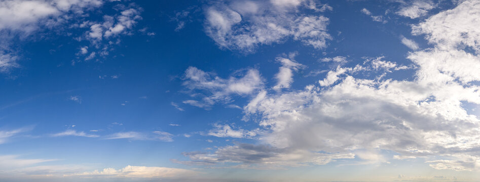 Blue Sky Cloudscape Panorama With White Clouds and Soft Sunlight Over Horizon