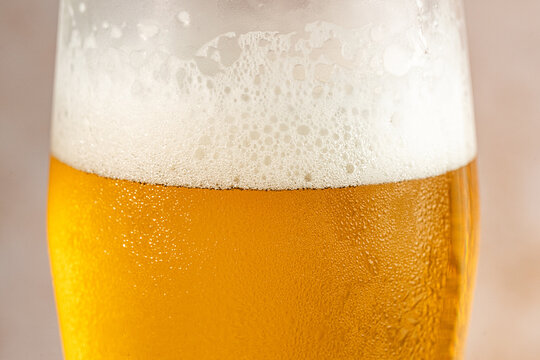 Closeup of a glass of beer with foam and water droplets 