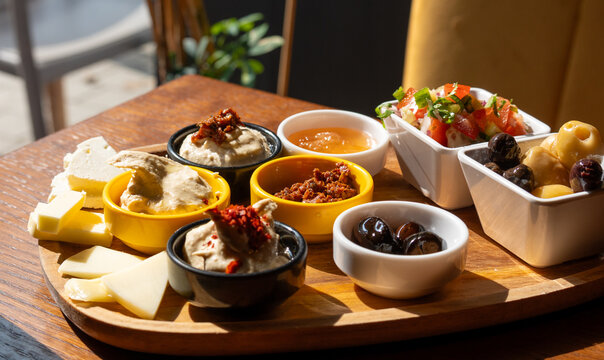 Breakfast appetizer snacks including cheese, hummus, pickled olives