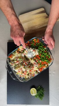 Person mixing the ingredients for traditional Olivier Ruska Salad in a Glass Bowl