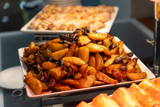 Close-up of golden roasted potato wedges on a white platter