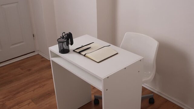 Right side view of desk with open notebook, stapler and scissors in holder, minimal office workspace, clean and modern business setup.
