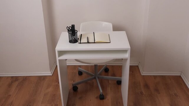 Top view of workspace with desk, chair, scissors, pen and stapler, minimal office setup, clean composition with copy space, modern work environment.
