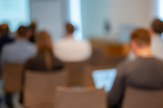 Blurred back view of people attending a business conference