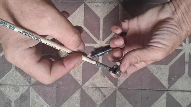 Hand holding a small paint brush applying lubricating grease to a metal nut in video footage