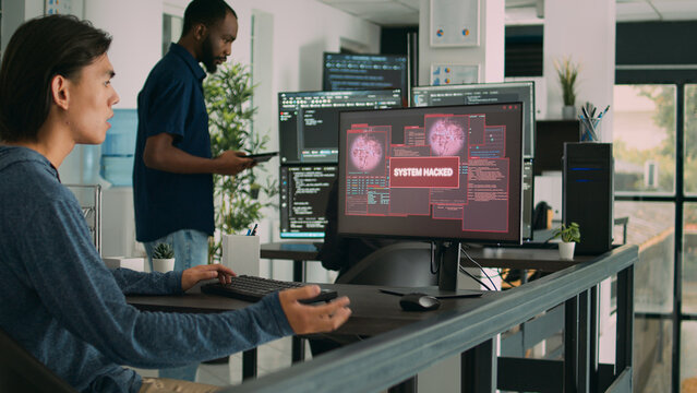 Asian programer focused on writing code encounters unexpected compiling error, being hacked in software development office. Coder having system failure and dealing with hackers.