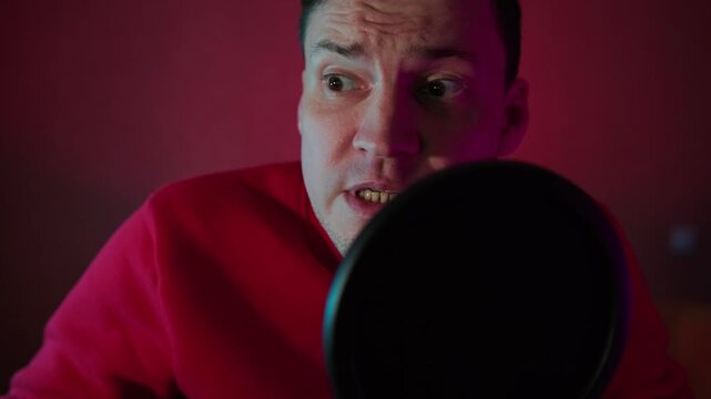 Man speaking into a microphone. Caucasian podcaster recording audio content in home studio. Professional broadcaster working on streaming media for digital broadcast.