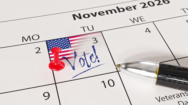 US midterm elections will take place on November 3, 2026. A calendar with a US flag, a thumbtack / pin and the text "Vote!" at the 3th of November. A pen lying on the calendar sheet. Zooming in.