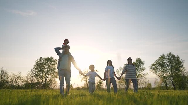 Toddler on father shoulders walking through meadow at golden sunset. Meadow glows in evening light. Toddler smiling under sunset sky. Father walks through quiet meadow. Peaceful toddler moment.