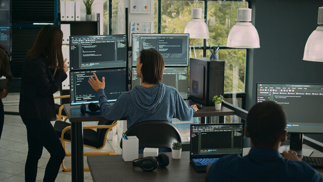 System engineer checking code on multiple monitors and working with app developer colleague in it agency office. Coder analyzing algorithm on screens, developing new user interface.
