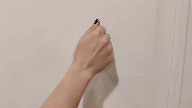 Close-up of a hand knocking on a door. Everyday communication, arrival and visitor concept, home or office entrance. Simple gesture symbolizing greeting, request, access and opportunity.