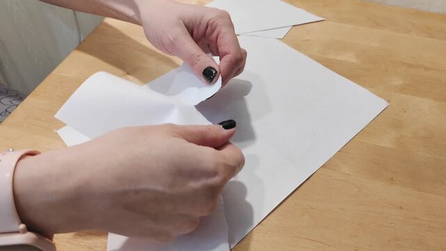 Close-up of hands tearing paper by hand. Concept of destruction, rejection, recycling, document disposal, creativity or stress relief. Simple manual action with paper on a clean background.