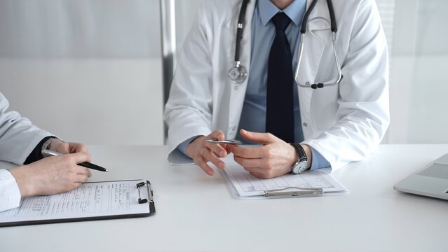 Medical professionals consulting, discussing patient health, reviewing test results at a clinic desk, offering healthcare advice. Medical team meeting