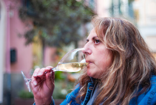 Mature woman portrait, with a glass of white sparkling wine, during a wine tasting experience.