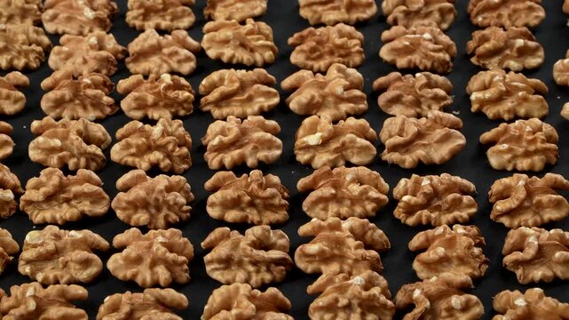 Densely packed infinite pattern of whole organic walnuts in shell. Shadowless harmonious soft lighting highlights the complex rugged texture. Premium conceptual background.