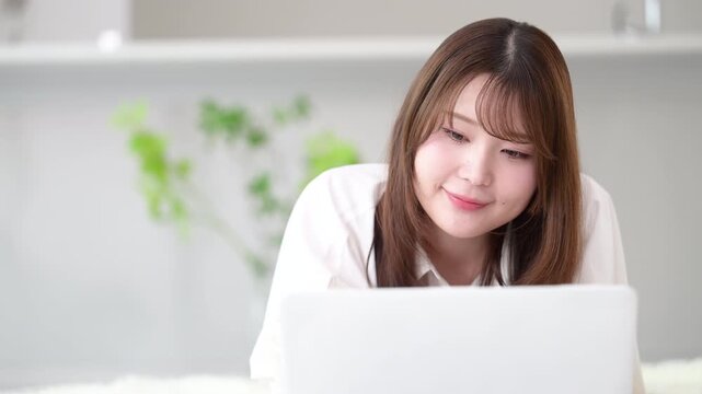 自宅でパソコンを使いながらタイピングする在宅勤務やリモート勤務や資格の勉強をする女性のデザイナーやフリーランスのビジネスイメージ　