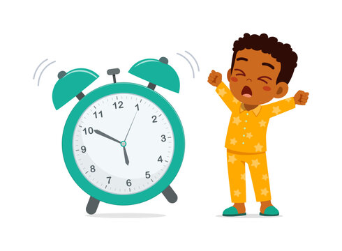 Sleepy Black boy yawning and stretching in yellow star pajamas waking up from loud ringing alarm clock