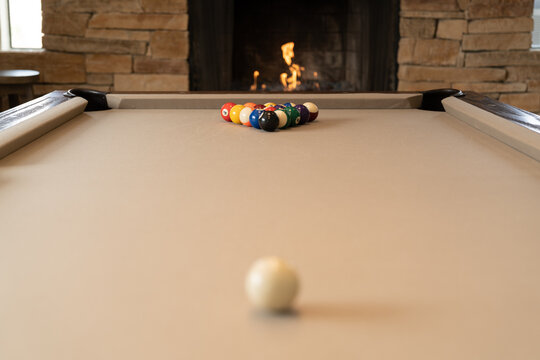 Close-up of a pool table with racked balls and fireplace in background