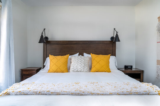 Modern farmhouse white bedroom with bed, decorative pillows, lamps