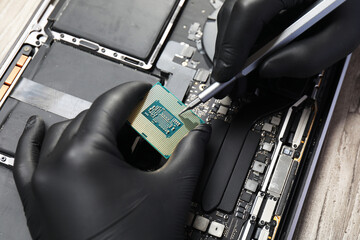 Naklejka premium Man repairing central processing unit of laptop with screwdriver at wooden table, above view