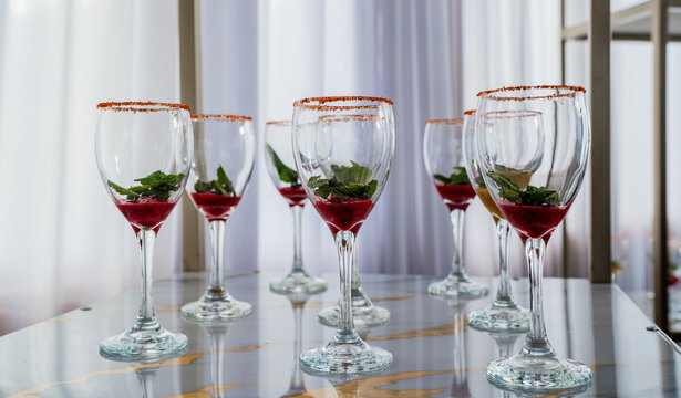 Copas de c&oacute;ctel con frutas rojas, menta y borde escarchado en elegante presentaci&oacute;n para evento