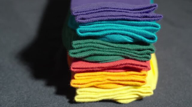 Close-Up Panning Shot of a Stack of Multicolored Socks on a Dark Background | Row of Neatly Folded Bright Hosiery | Daily Routine and Household Organization Concept