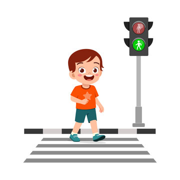 A happy young boy smiling while walking across a zebra crosswalk with a green pedestrian traffic light signal