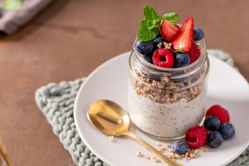 Healthy Chia Seed Pudding in a Glass Jar Topped with Fresh Berries and Granola © homydesign
