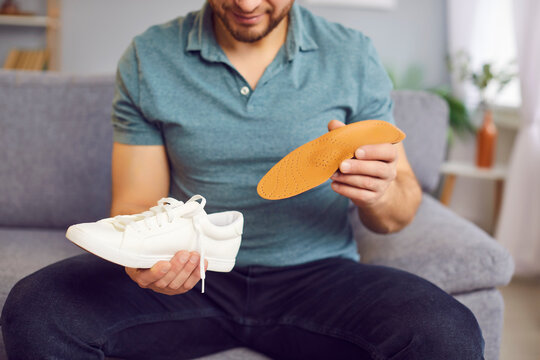 Man orthopedist carefully inserting an orthotic insole into a shoe to provide orthopedics support and health for the feet. Medical procedure ensures proper foot alignment and alleviates discomfort.