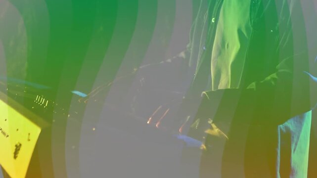 Male musician leaning forward, playing keys and turning knobs, light bands sweeping, creating music