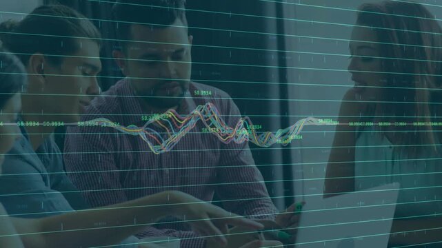 Diverse coworkers leaning over laptop, pointing at animated graph while using smartphone in office