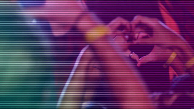 Vertical video: Women raising hands at concert forming heart celebrating band, yellow wristbands