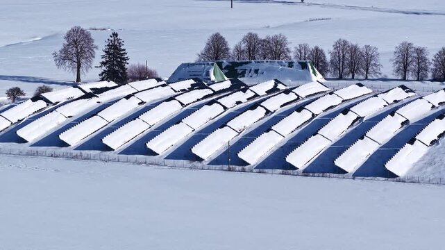 Aerial winter view of a rural biogas plant and silage storage beside snowy fields, showing renewable farm infrastructure and cold-season energy production.