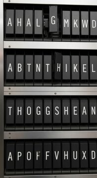 Close-up of a vintage split-flap display showing random letters, evoking a sense of retro technology and communication.