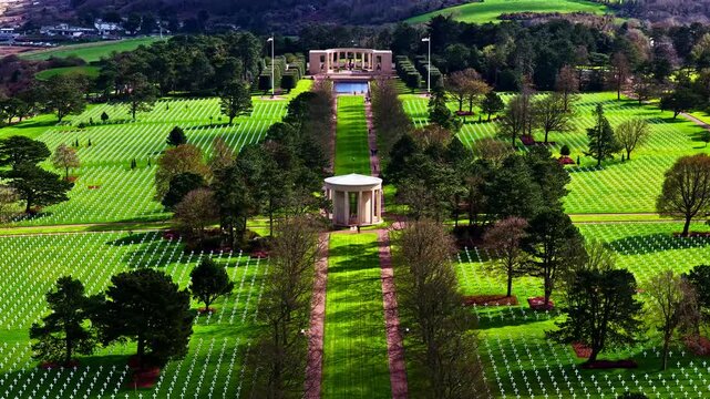 Aerial drone flyover reveals iconic rotunda chapel and thousands of white cross grave rows at Normandy American Cemetery in Colleville-sur-Mer, France