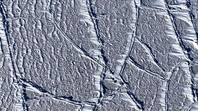 Aerial view of icy landscape with patterns in winter sunlight