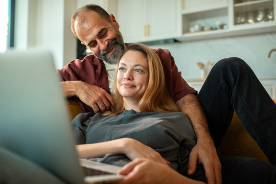 Smiling couple relaxing with laptop on couch at home