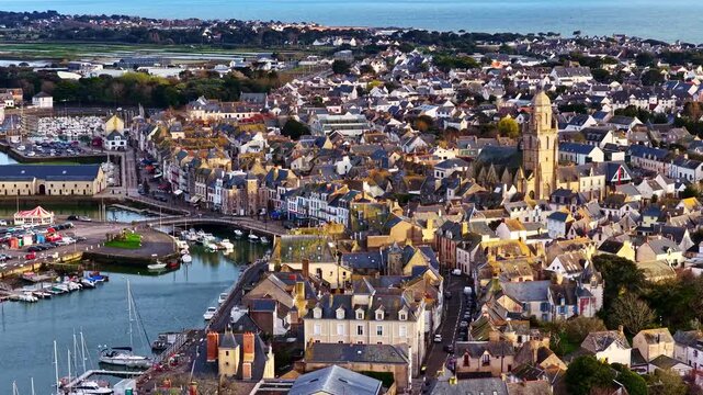 Historic harbor town with church tower marina and dense coastal buildings in Le Croisic France, aerial establishing dolly at sunset
