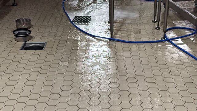 Wet tile floor with hose in industrial kitchen cleaning scene