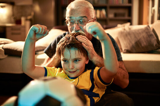 Grandfather and grandson cheering soccer match at home