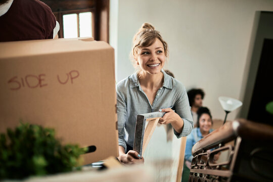 Smiling woman and friends moving belongings upstairs in new home