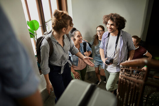 Diverse friends arriving with luggage in hostel stairwell