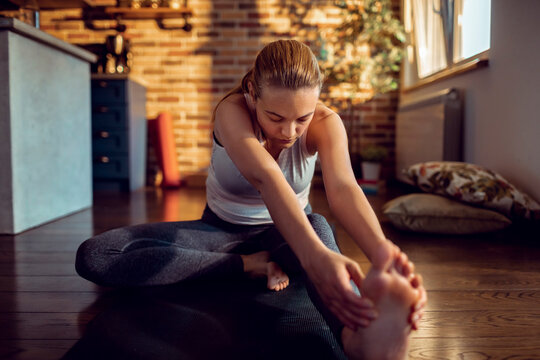 Young woman stretching on yoga mat at home
