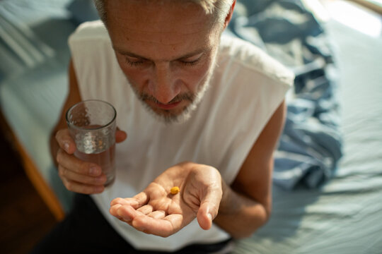 Senior man taking morning medication with water at home