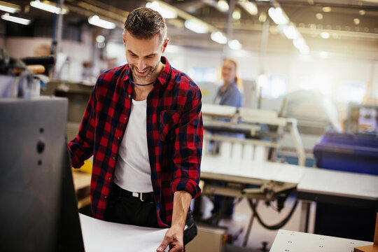 Smiling print shop worker operating industrial machine