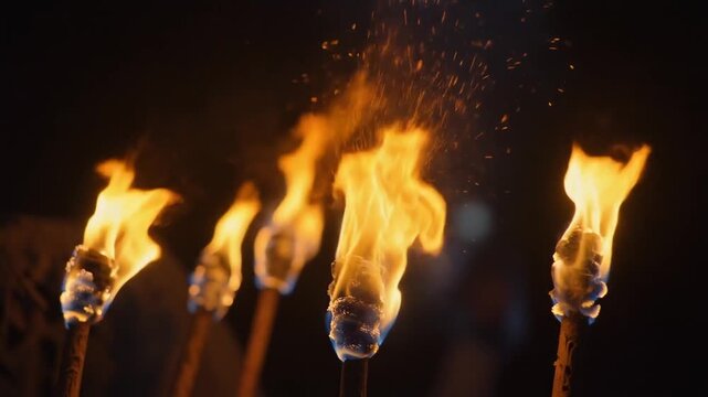 Cinematic Slow Motion of Multiple Torches Burning with Bright Orange Flames in a Row, Dark Background