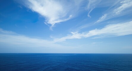 Fototapeta premium Wide open sky filled with drifting clouds and deep blue sea